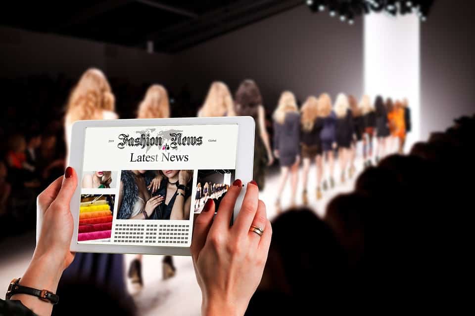 A person holding a tablet while watching a fashion show