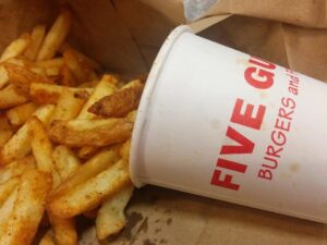 five guys fries pouring out of a cup