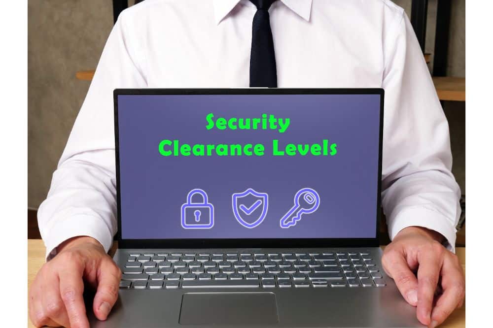 man holding laptop with security clearance written on screen